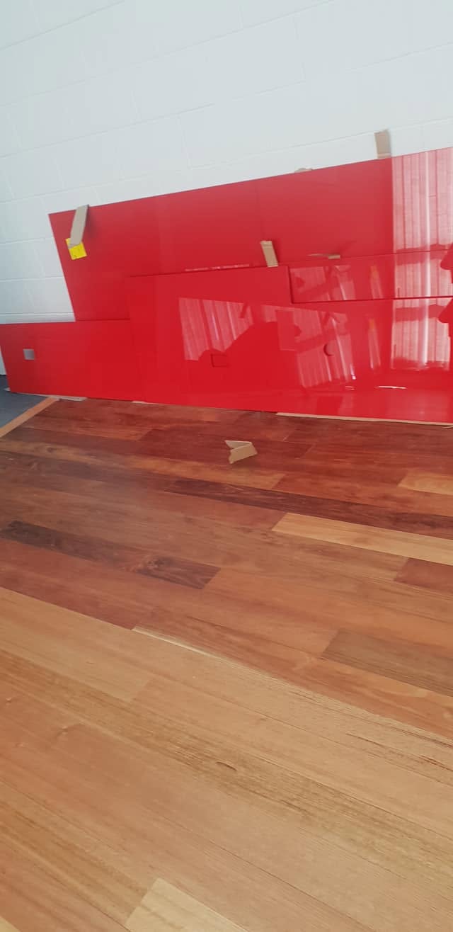 Colour back sprayed glass splashback standing above timber flooring