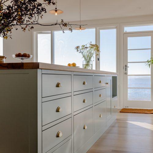 Sage green island with brass cup handles in a Blackmans Bay kitchen by the water