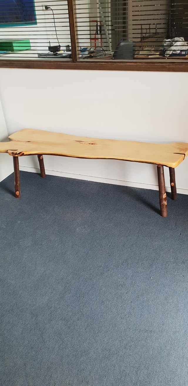 Live-edge timber bench seat on turned legs after clear coating