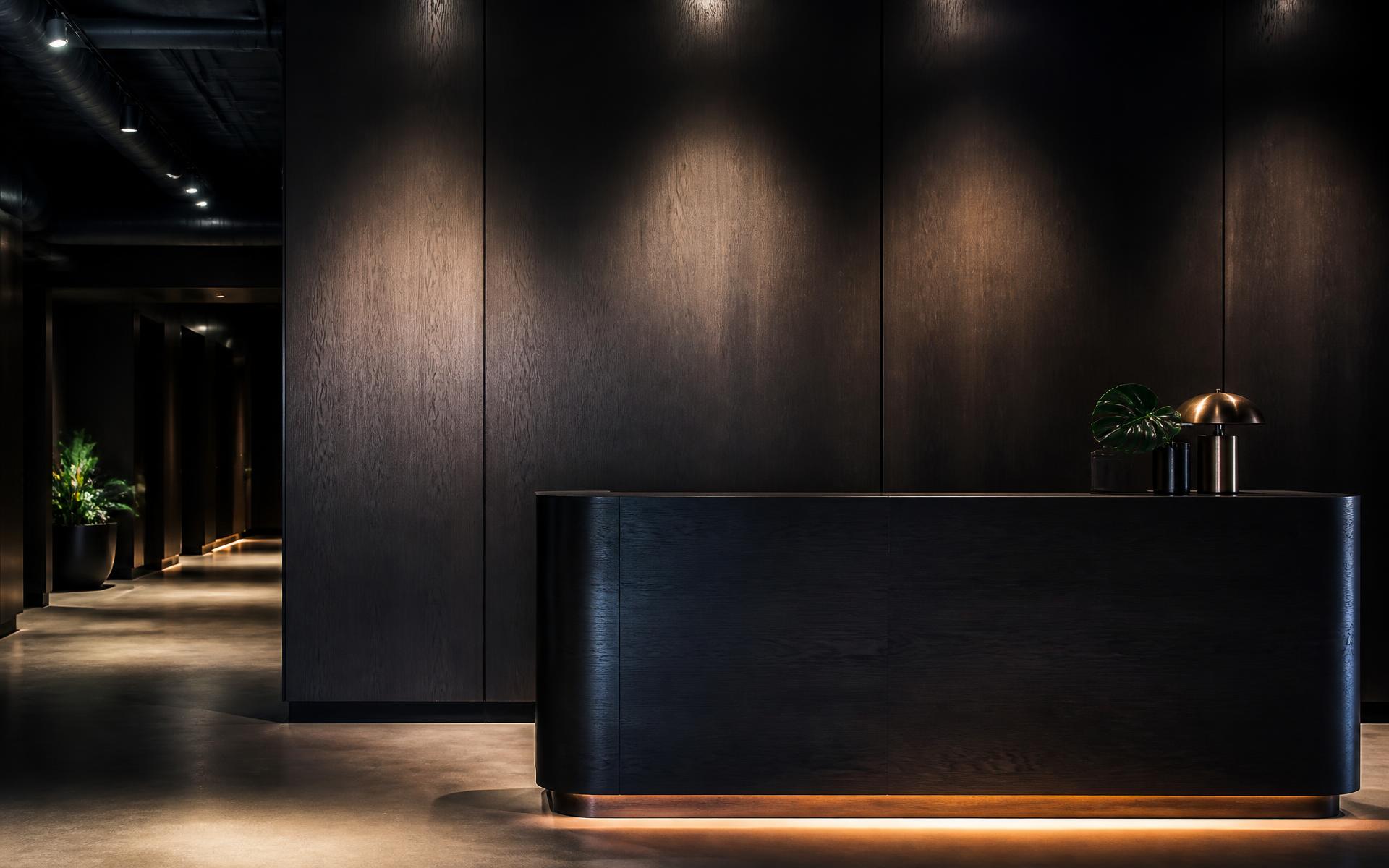 Commercial timber finishing — sprayed dark timber reception joinery and wall panelling in a Hobart fitout